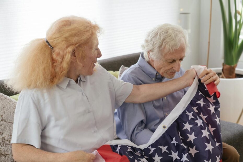 Senior veteran couple at home holding an American flag, representing the families Embark Care supports through VA home care benefits in Texas and Arkansas.